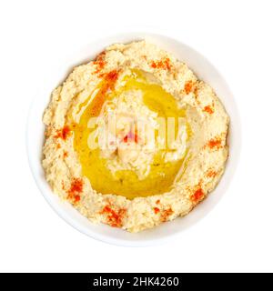Hummus dip with paprika powder and olive oil, in a white bowl. Middle Eastern dip, spread or savory dish made of cooked, mashed chickpeas. Stock Photo
