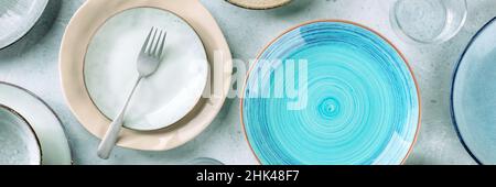 Modern tableware panorama with a blue plate, a fork, and many other clean dishes. Elegant catering panoramic banner, shot from above Stock Photo