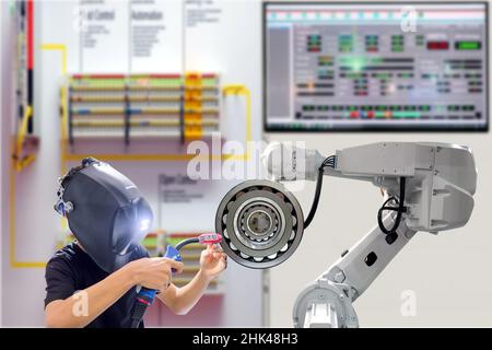 Close-up technician on safety mask protection working with workpieces via industry gripping robot on blurred workshop of smart factory background Stock Photo