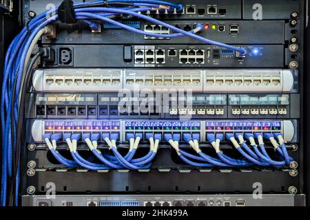 Back I/O port of server rack and blue cable connected to LAN port for work on networking communication on DATA Center information Stock Photo