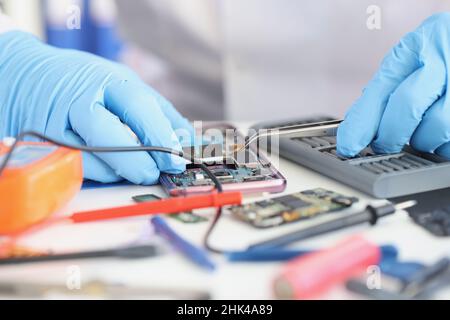 Master repairman inserting microchip into mobile phone closeup Stock Photo