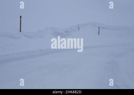Frosty slippery mountain road with traffic signs buried by the snow after a heavy snowfall Stock Photo