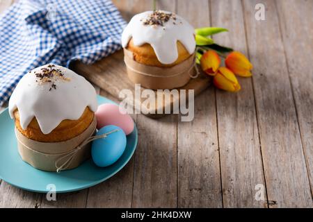 Traditional Easter cake, colorful eggs and tulips on wooden table. Stock Photo