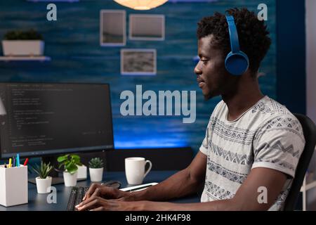 It businessman wearing headphones programming codes for firewall server on computer working remote from home. Hacker man typing infographics javascript writing artificial intelligence algorithm Stock Photo