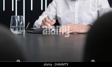 Man hands writing in diary. Employee sitting at office desk. Business planning concept. . High quality photo Stock Photo