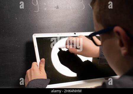 Boy drawing with chalk on laptop Stock Photo