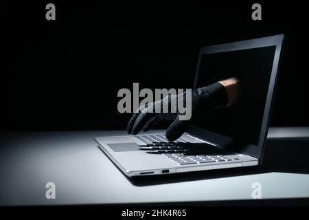 internet fraud and cyber attack concept. thief hand out of laptop screen Stock Photo