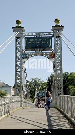 Chester, England - July 2021: People walking across the Queens Park Bridge, a suspension bridge over the River Dee near the city centre. Stock Photo