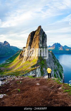 Person standing in front of tall Segla Mountain and fjords at dawn, Senja island, Troms county, Norway, Scandinavia, Europe Stock Photo