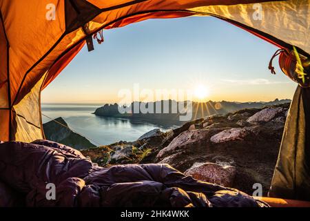 Warm lights of sunrise view from the inside of hiker's tent, Senja island, Troms county, Norway, Scandinavia, Europe Stock Photo