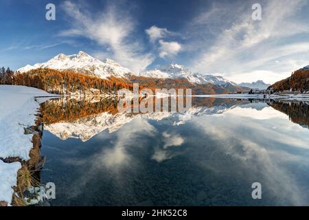 Autumn woods and snowcapped mountains mirrored in the clear water of Champfer lake at sunset, Engadine, Graubunden, Switzerland, Europe Stock Photo