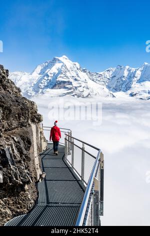 Woman admiring Jungfrau mountain in the fog from the Thrill Walk panoramic walkway, Murren Birg, Bern Canton, Swiss Alps, Switzerland, Europe Stock Photo