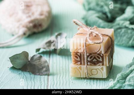 Three pieces of natural soap with eucalyptus branches on light green background, wellness concept Stock Photo