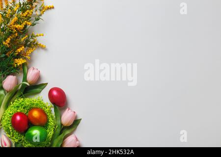Easter composition. Multi-colored pearl eggs in a nest of tulip flowers on a gray background with copy space. Stock Photo