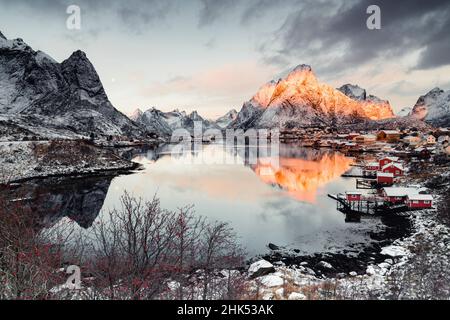 Clouds at dawn over traditional Rorbu and Olstind mountain reflected in sea, Reine Bay, Nordland, Lofoten Islands, Norway, Scandinavia, Europe Stock Photo