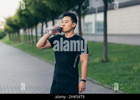 asian man drinks water after fitness workout and jogging tired Stock Photo