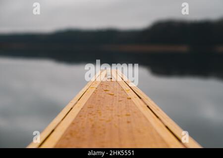 Point of view of a wooden canoe bow on the lake. Paddling in autumn or spring, no people