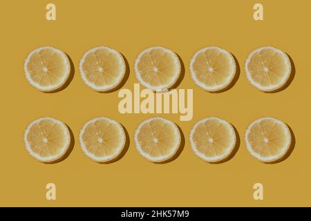 Set of sliced fresh juicy lemons isolated on yellow background. Pattern Stock Photo