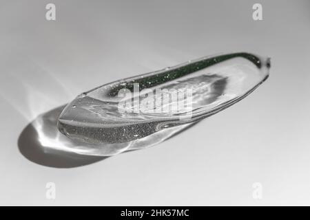 Cosmetic gel or serum swatch on a gray background with sun shadow. Skincare product smear smudge sample. Liquid cream with bubbles texture Stock Photo