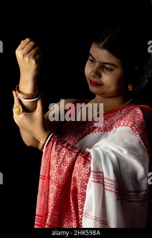 An Indian woman in red saree wearing bangles with smiling face on black background Stock Photo