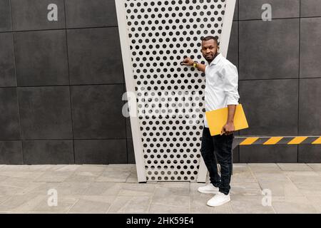 Portrait of serious male employee looking at the side, posing for the photo at the grey background. Stylish handsome businessman standing near the off Stock Photo
