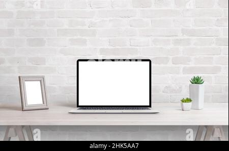 Laptop mockup on work desk. Work at home concept. Clean desk with photo frame and plants Stock Photo