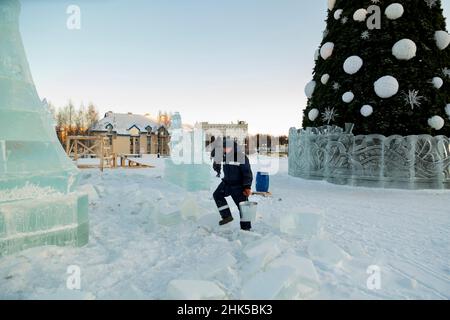 Worker with a bucket in hand at the assembly site of the ice town Stock Photo