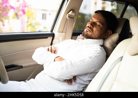 tired cab driver resting or sleeping by pushing car seat during break time - concept of overworked, exhausted and low business or no passengers Stock Photo