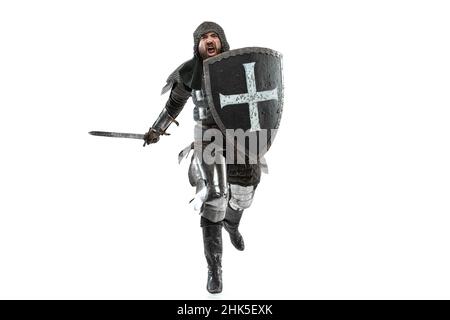 Portrait of brutal seriuos man, medieval warrior or knight with dirty wounded face running with big sword isolated over white background. Stock Photo