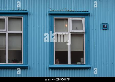 The windows of a traditional Reykjavik sheet metal house which is painted bright blue Stock Photo