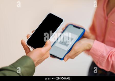 Unrecognizable Man Using Smartphone Scanning QR Code On Lady's Phone Stock Photo
