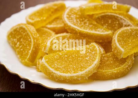 marmalade lemon slices on a white plate on a wooden table indoor closeup Stock Photo