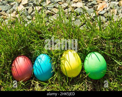 Four painted and decorative Easter eggs in the grass. Top view, copy space. Stock Photo