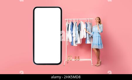 Woman Standing Near Cellphone Screen Shopping Online Choosing Clothes, Studio Stock Photo