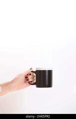 Black coffee mug mockup for design demonstration. Stylish cup mock up in female hands. Stock Photo