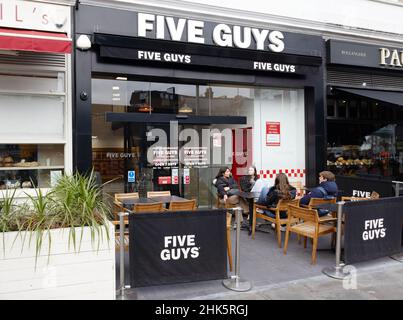 Five Guys UK; People eating outside a Five Guys restaurant, an american food chain with restaurants across the UK, South Kensington, London UK Stock Photo