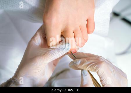 A Podiatrist doctor who takes care of a woman's toenails. Cosmetic procedures of the feet Stock Photo