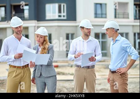 Focused middle-aged female inspector inspecting building plans Stock Photo
