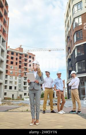 Focused construction inspector scrutinizing project documentation outdoors Stock Photo