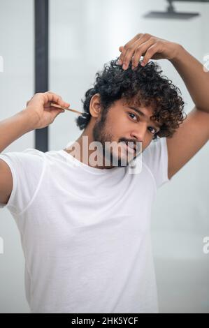 Cute Indian male focused on hairstyling procedure Stock Photo