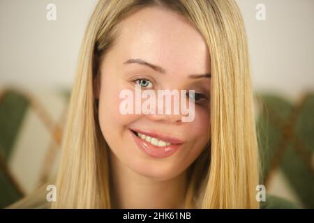 Domestic violence victim living happy life. Beautiful blonde woman with face scars and prosthetic eye looking in camera with cheerful toothy smile. In Stock Photo
