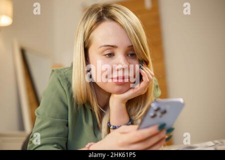 Domestic violence survivor woman with facial scars and prosthetic eye living happy life with mobile phone. Abuse victim with scar on face communicatin Stock Photo