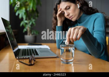 Unhealthy businesswoman taking painkiller from headache or migraine at workplace in office Stock Photo