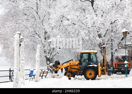 UZHHOROD, UKRAINE - FEBRUARY 2, 2022 - A loader tractor is seen on the street during a snow removal effort by municipal services in winter, Uzhhorod, Stock Photo