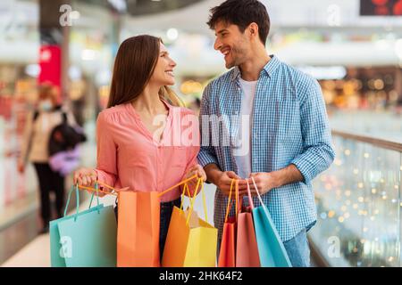 Happy Couple Shopping Holding Paper Shopper Bags In Mall Stock Photo