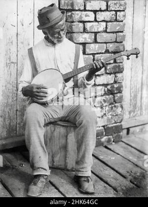 V G Schrek photograph entitled Melody - An elderly African American man sitting outside playing a banjo - 1902 Stock Photo
