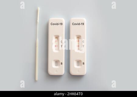 Two covid antigen rapid test kits and a nasal swab with positive results on white background, covid-19 lab testing concept Stock Photo