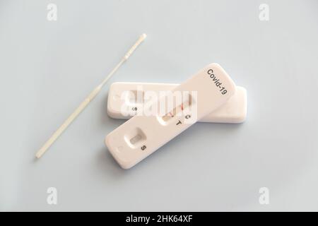 Two covid antigen rapid test kits and a nasal swab with positive results on white background, covid-19 lab testing concept Stock Photo