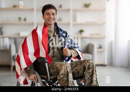 Cheerful military guy in wheelchair with flag of the US Stock Photo