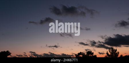 Twilight light color orange the sky. Scattered cloud on dark blue sky background. Stock Photo